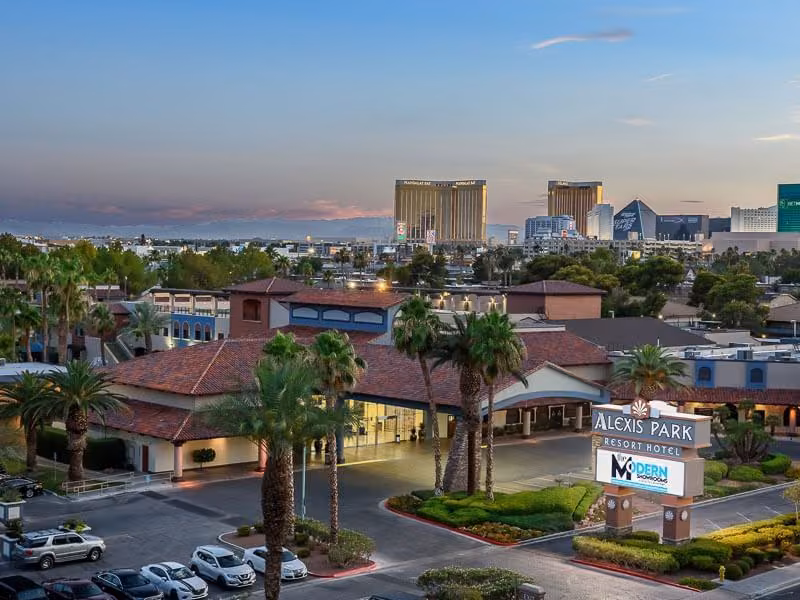 Aerial view of Alexis Park Resort with the Las Vegas Strip skyline at dusk