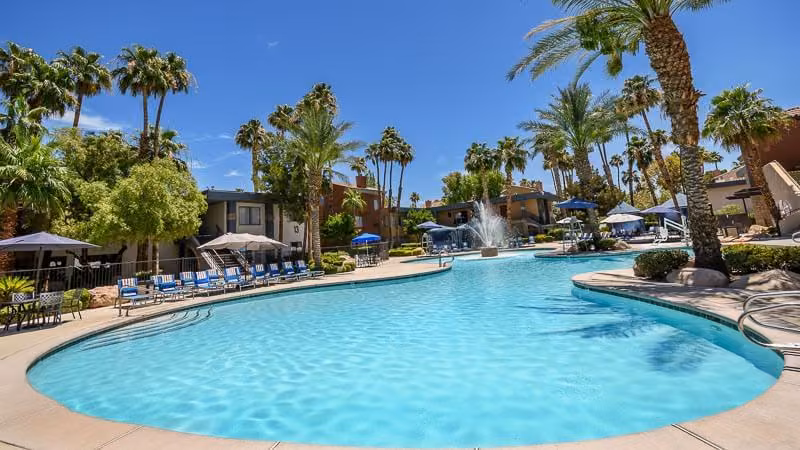 Resort pool surrounded by palm trees at Alexis Park