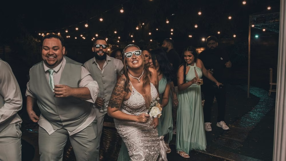 Bride dancing with wedding party under string lights on the dance floor