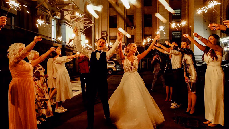 Bride and groom celebrating through a sparkler send-off aisle
