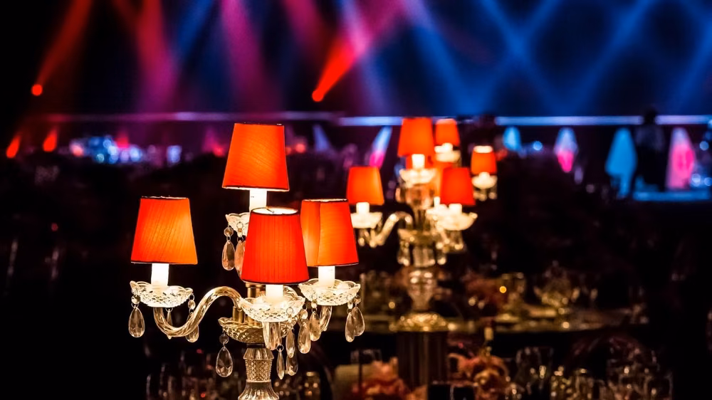 Red glass candelabras glowing under blue and red uplighting at an evening reception