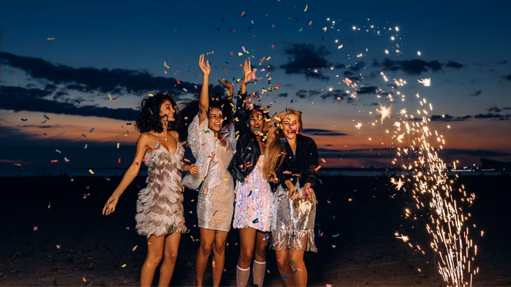Guests celebrating with confetti and sparklers at sunset