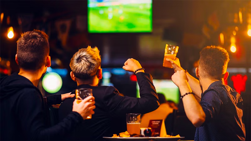 Watch party spread with beer and wings in front of a big screen